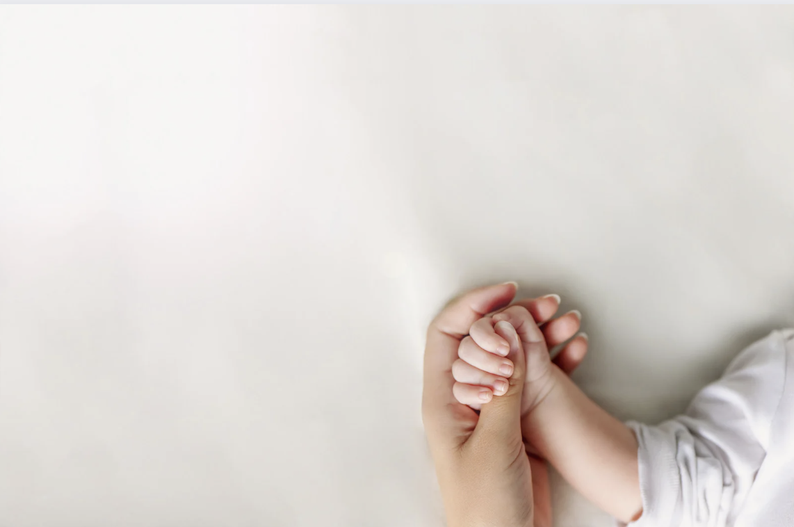 mom holding baby's hand before maternity leave ends
